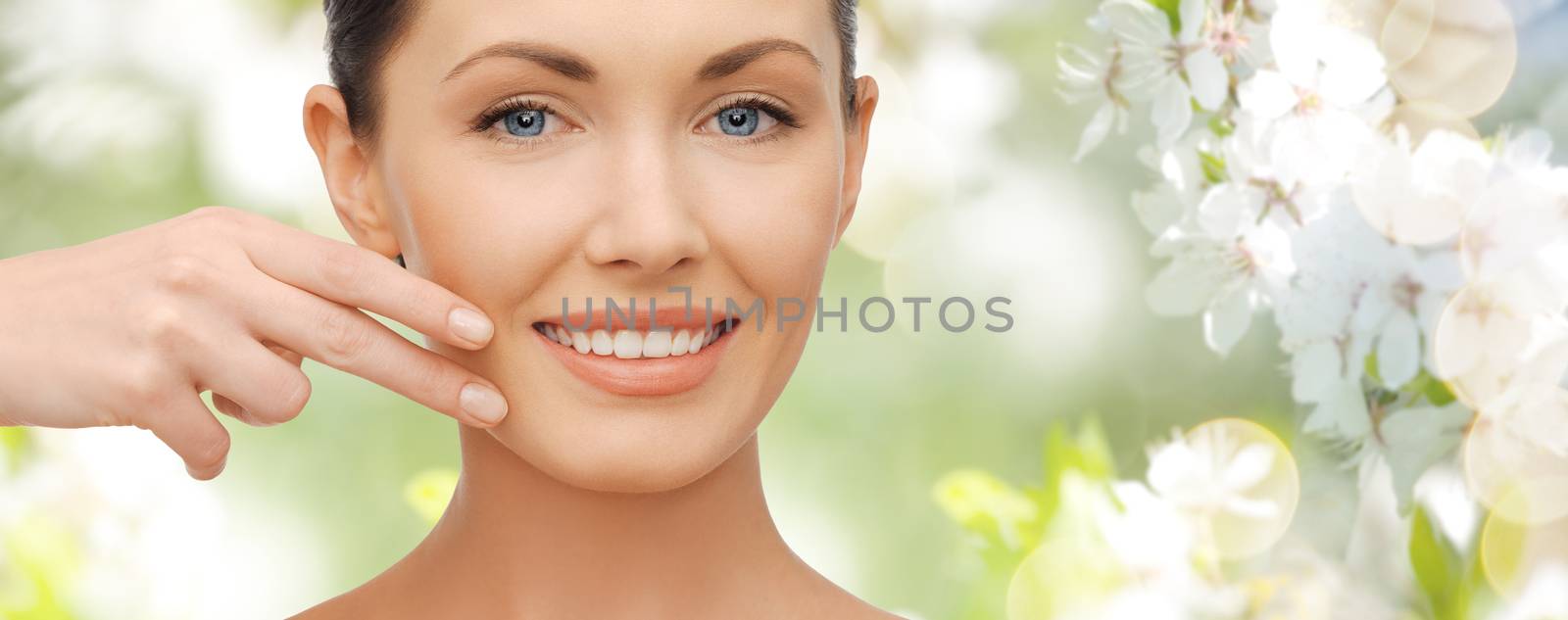 healthcare, people and beauty concept - beautiful woman touching her face skin over green summer garden and cherry blossoms background