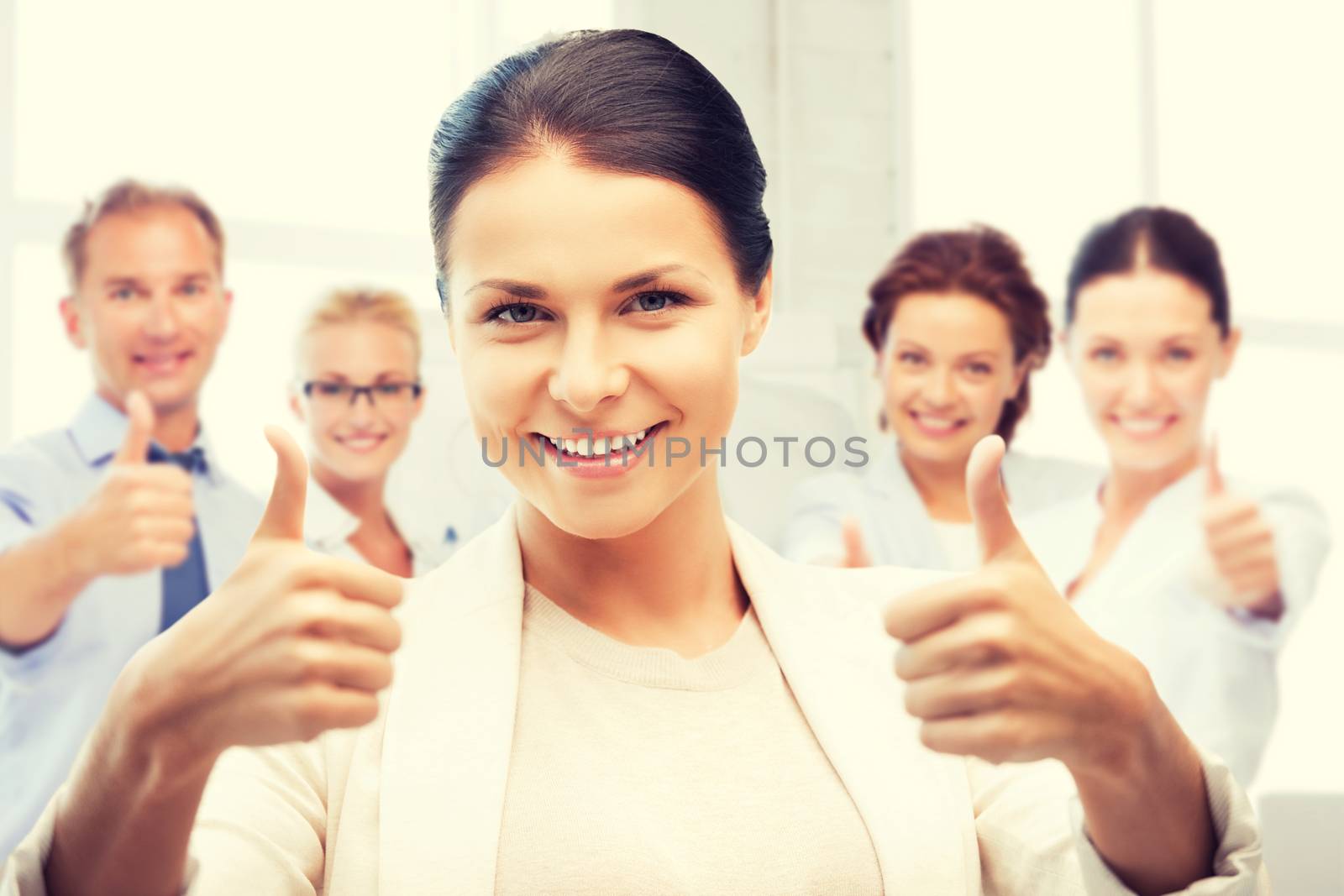 businesswoman showing thumbs up in office by dolgachov