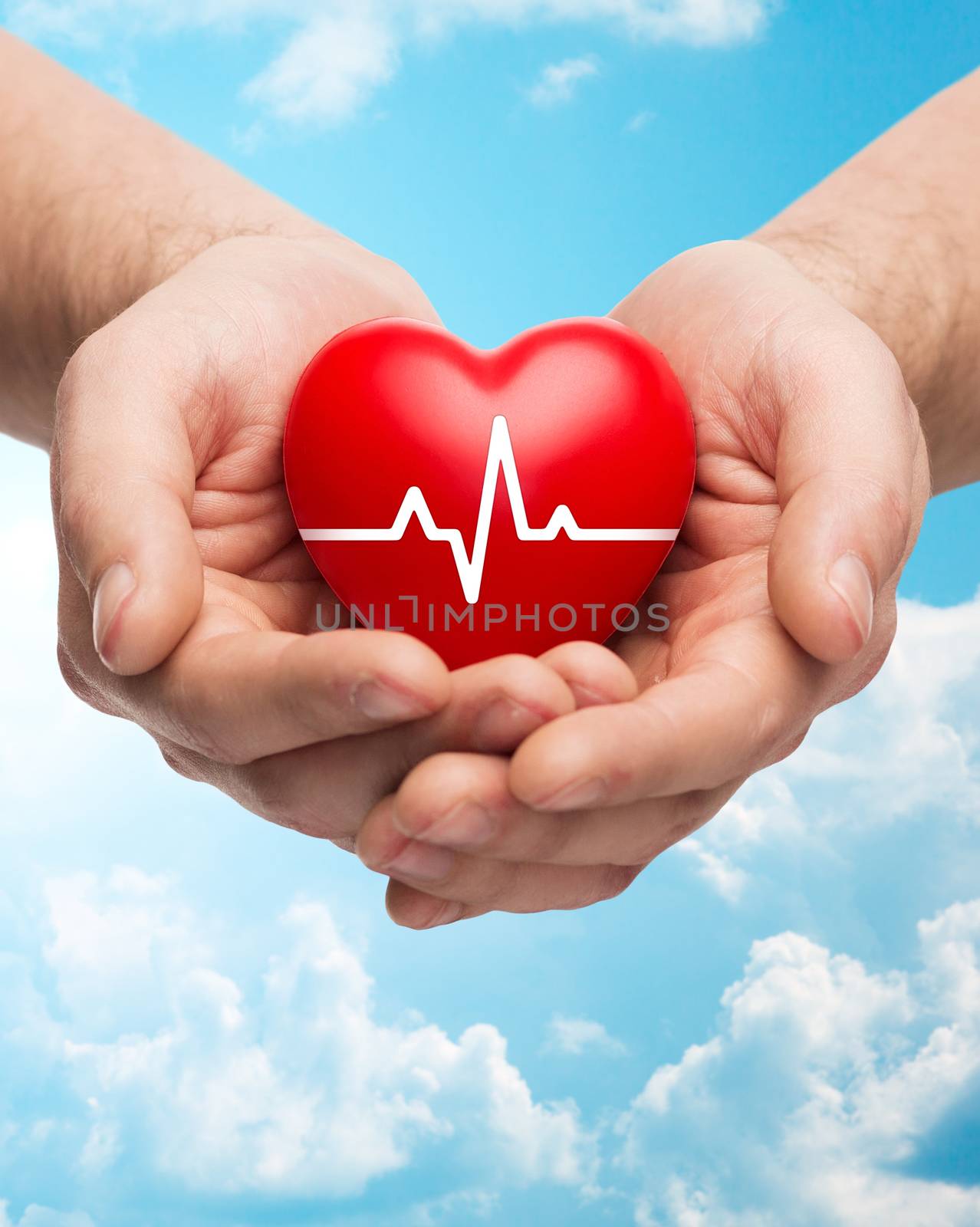 close up of hands holding heart with cardiogram by dolgachov