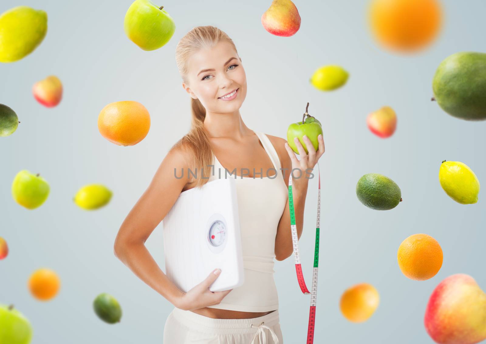 healthy eating, diet, weight control and people concept - happy young woman with scale, green apple and measuring tape over gray background with falling fruits
