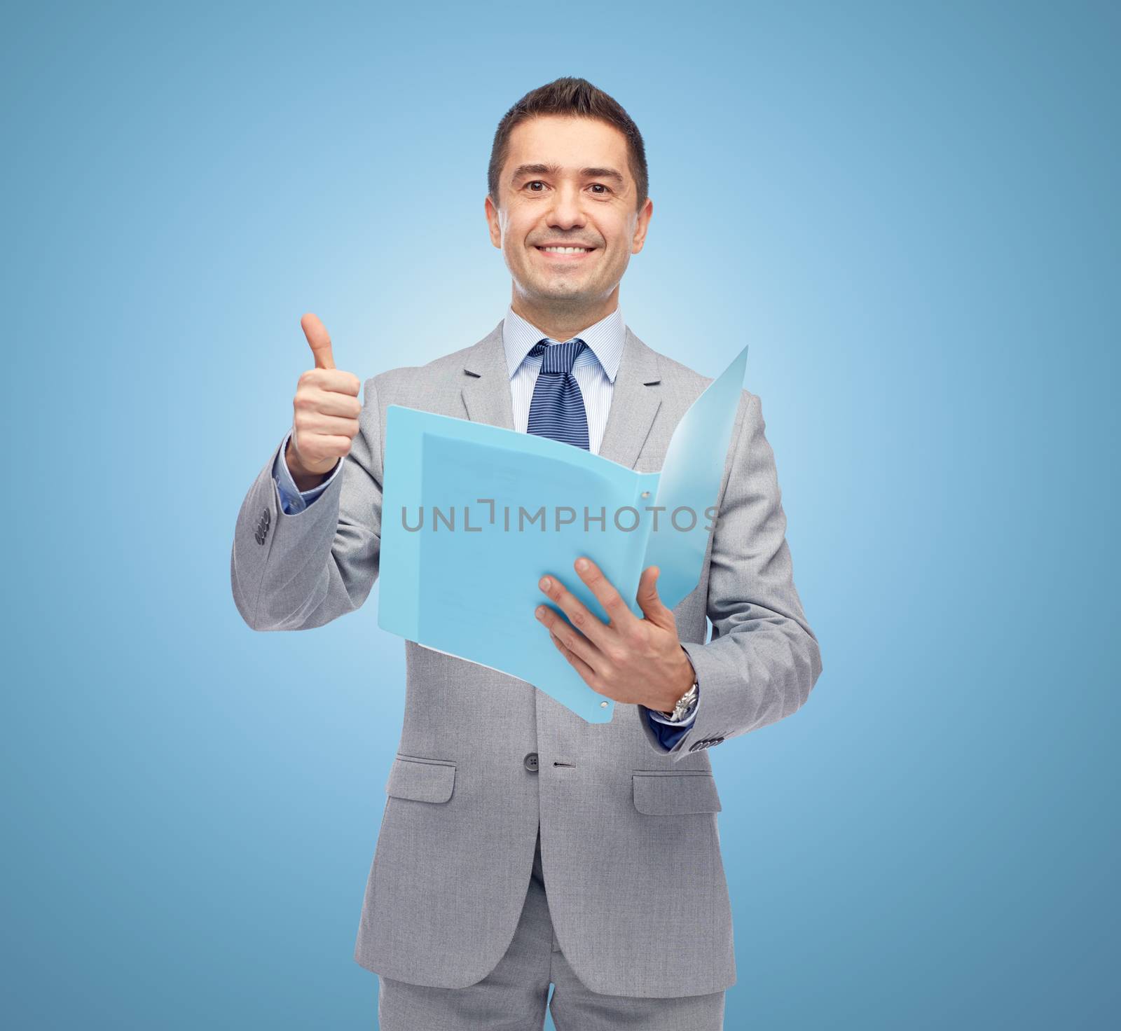 business, people, finances and paper work concept - happy smiling businessman in suit holding folder and showing thumbs up over blue background