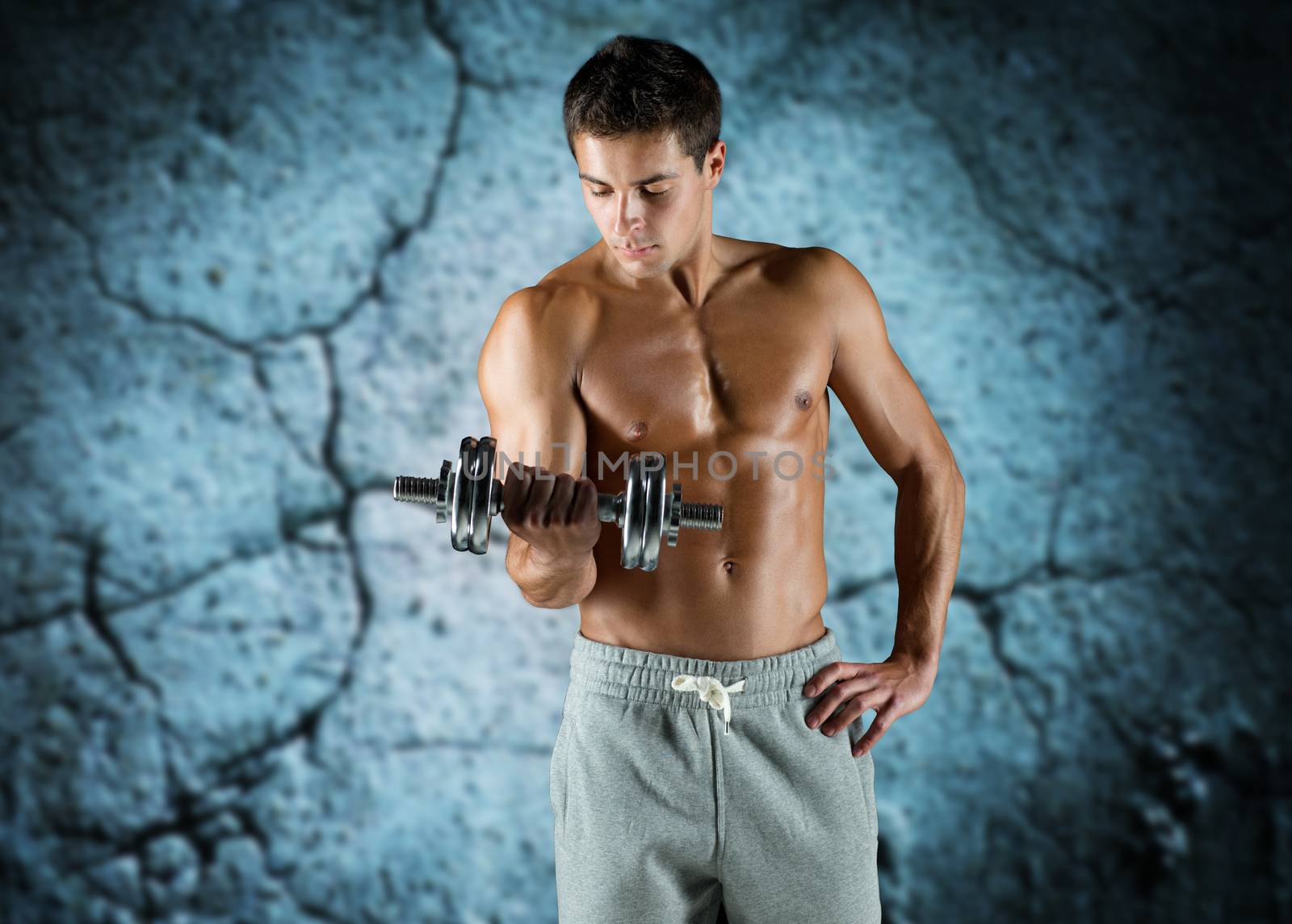 young man with dumbbell flexing biceps by dolgachov