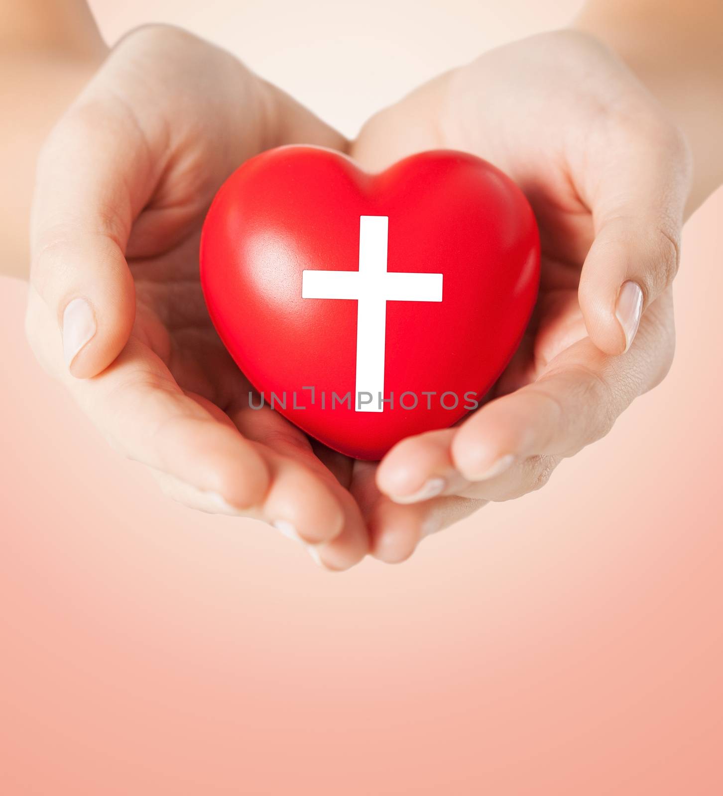 close up of hands holding heart with cross symbol by dolgachov