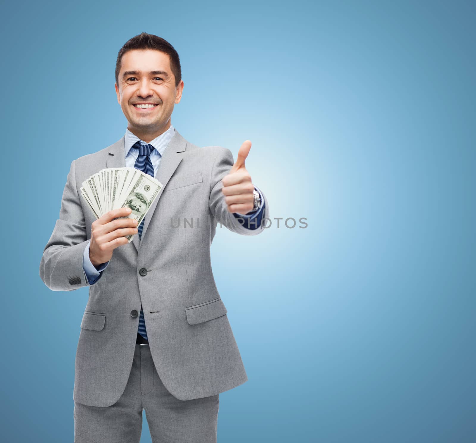 smiling businessman with money showing thumbs up by dolgachov