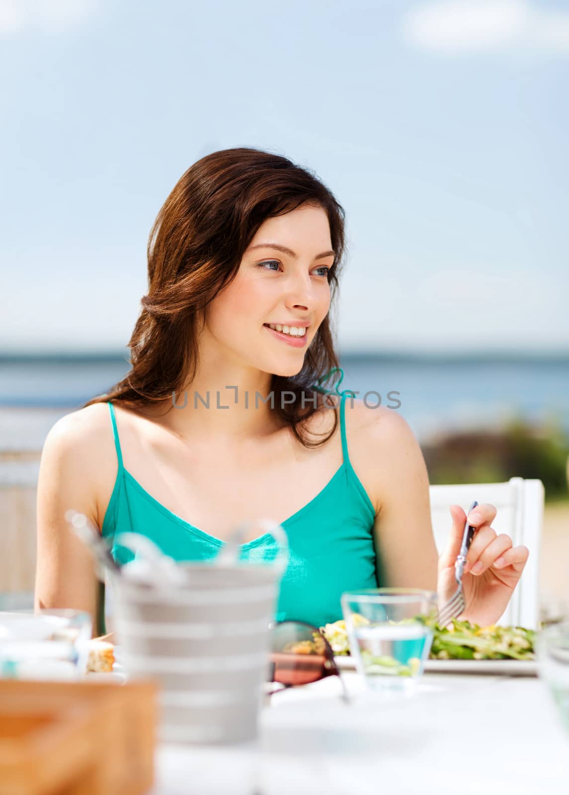 summer holidays and vacation - girl eating in cafe on the beach