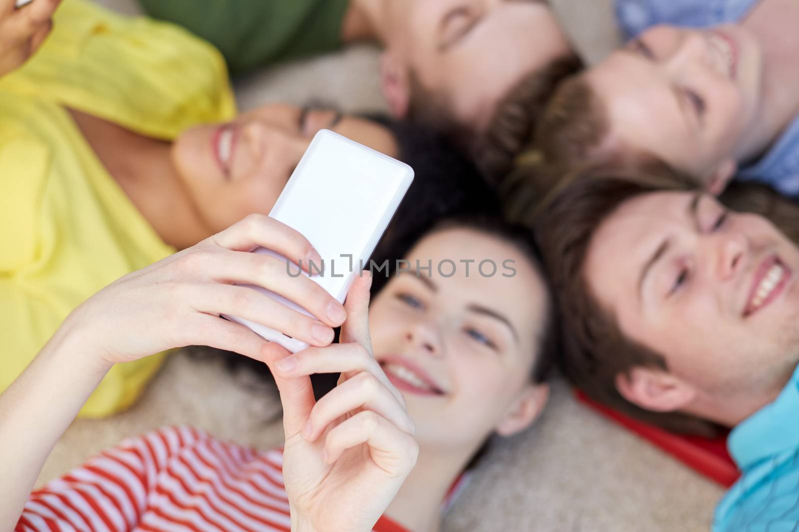 education, people and technology concept - close up of students or friends with smartphones lying on floor in circle