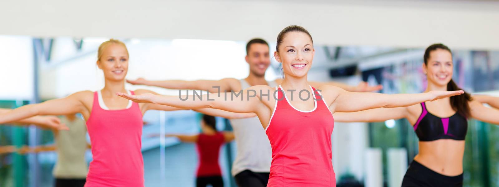 group of smiling people exercising in the gym by dolgachov