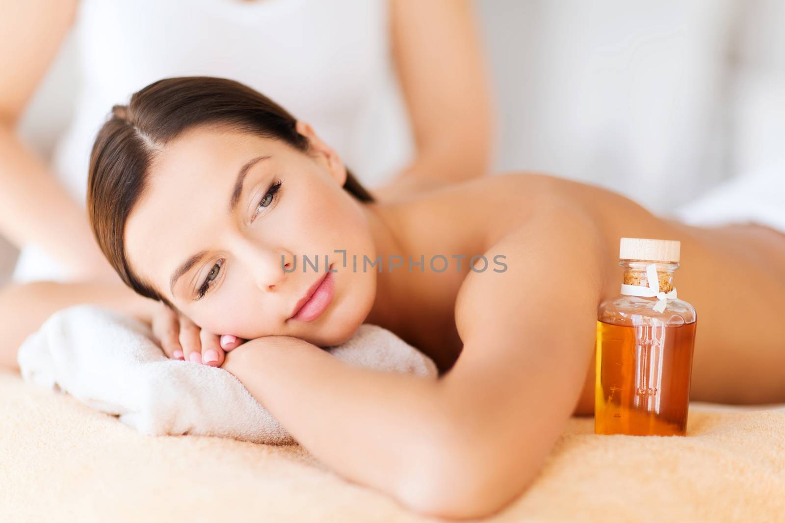 beauty and spa concept - beautiful woman in spa salon getting oil treatment