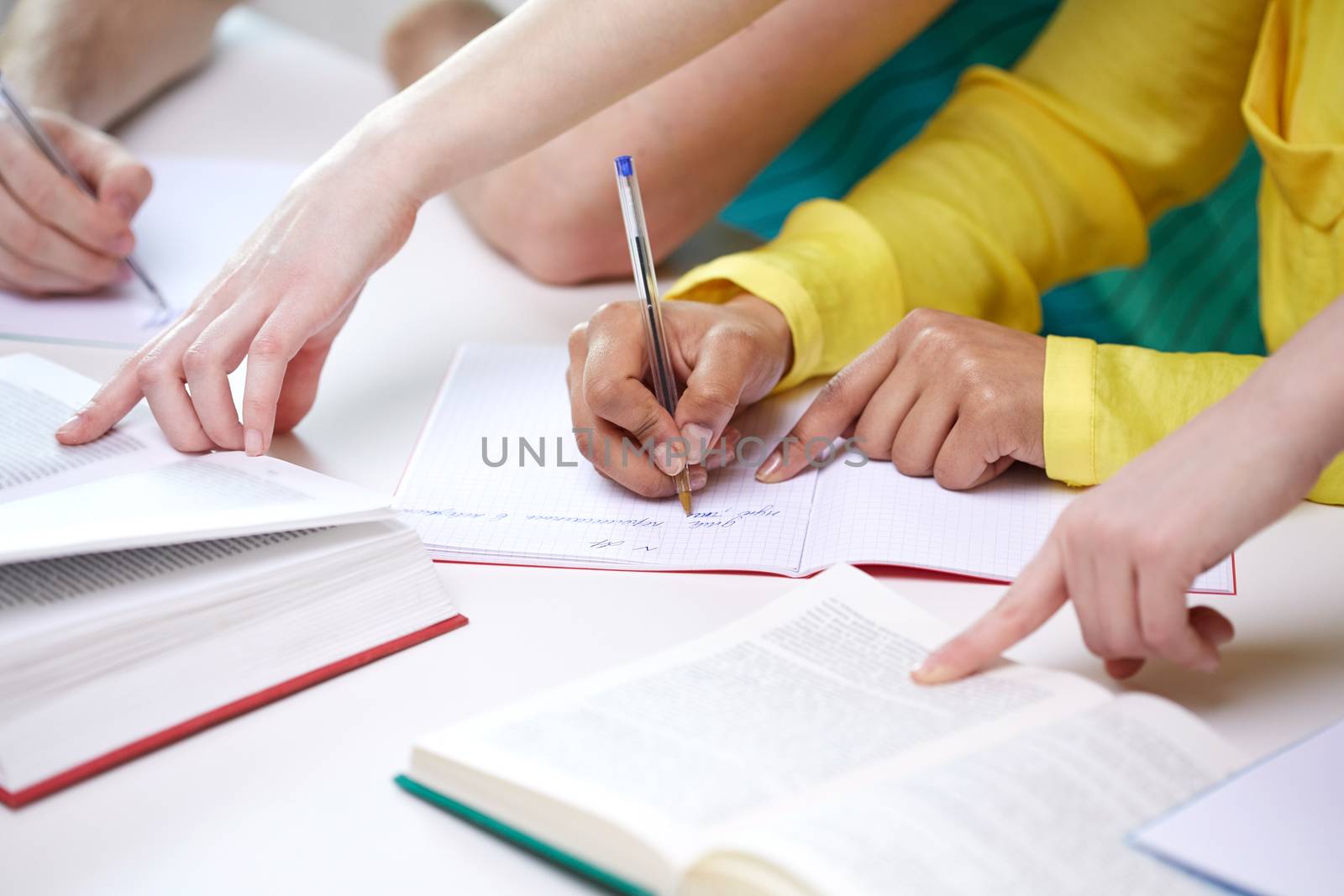 education, people and school concept - close up of students hands with textbooks writing to notebooks at school