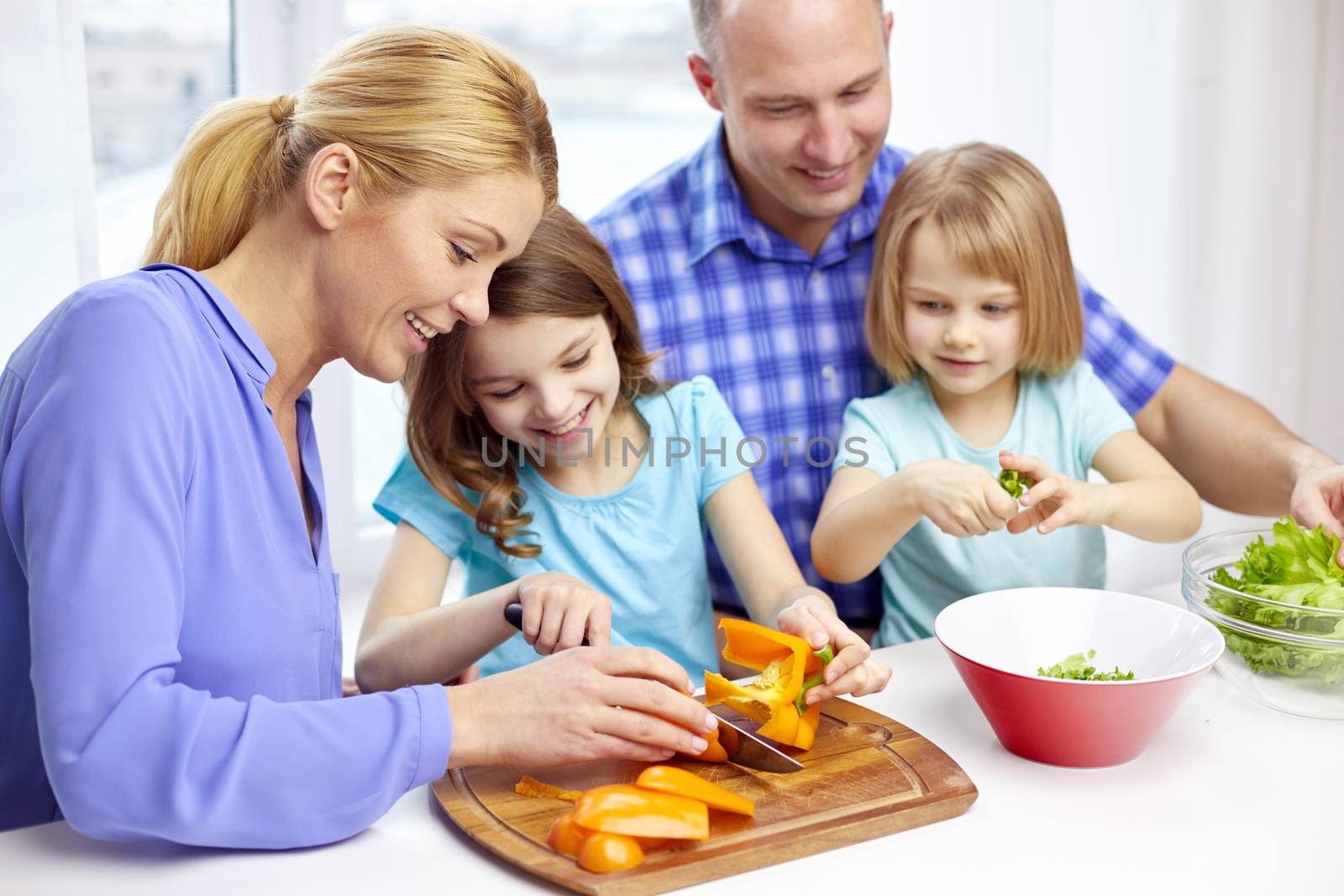 food, children, culinary and people concept - happy family with two kids cooking vegetables at home