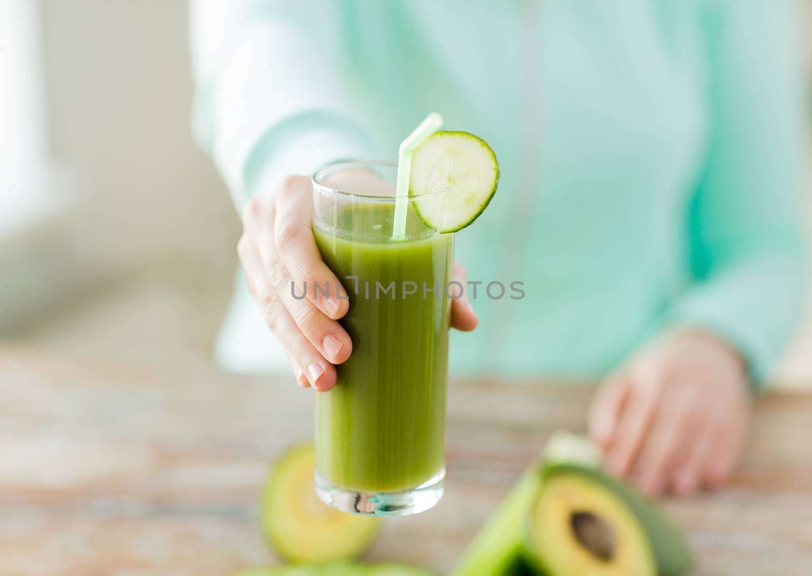 healthy eating, food, dieting and people concept - close up of woman hands with green fresh juice and vegetables sitting at table