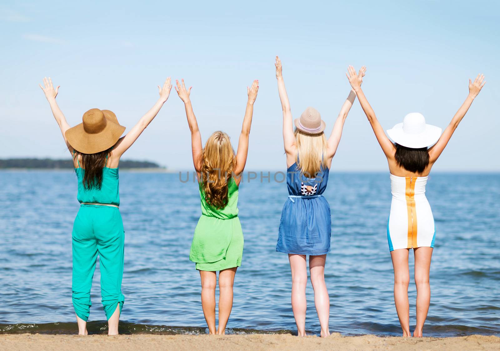summer holidays and vacation - girls with hands up on the beach