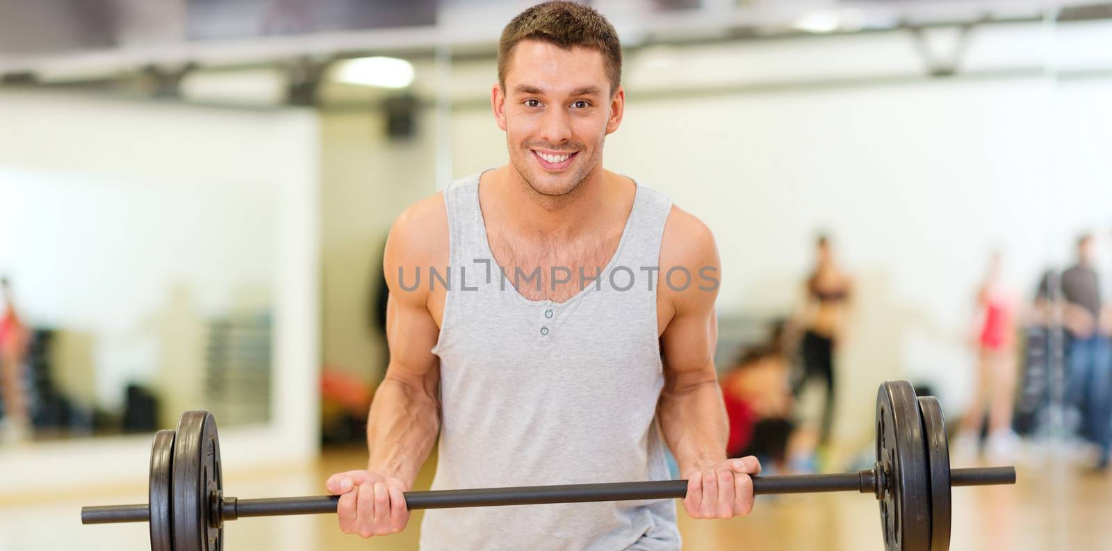 smiling man with barbell in gym by dolgachov