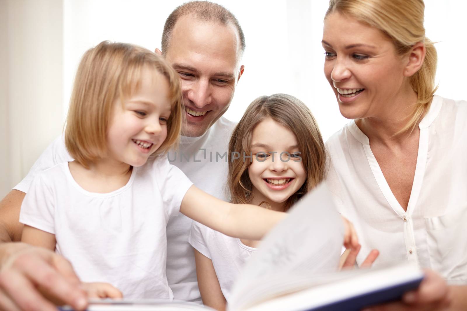 family, childhood, literature and people - happy mother, father and little girls reading book at home