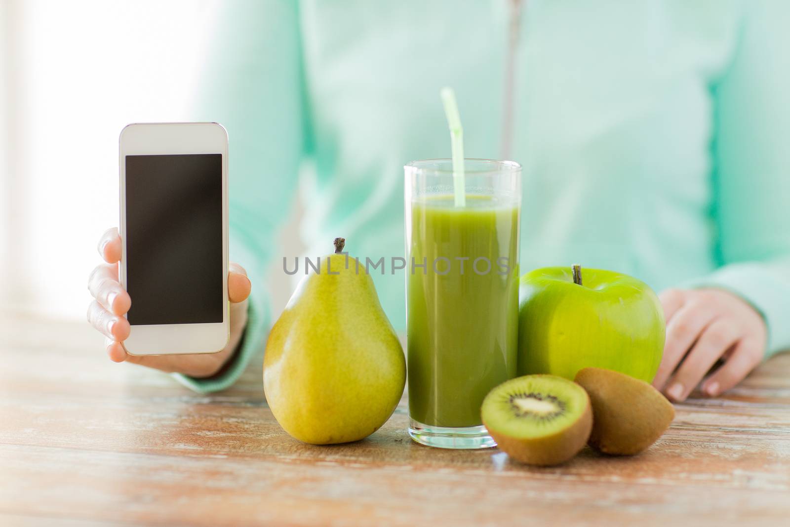 healthy eating, technology, diet and people concept - close up of woman hands with smartphone, fruits and fresh juice sitting at table