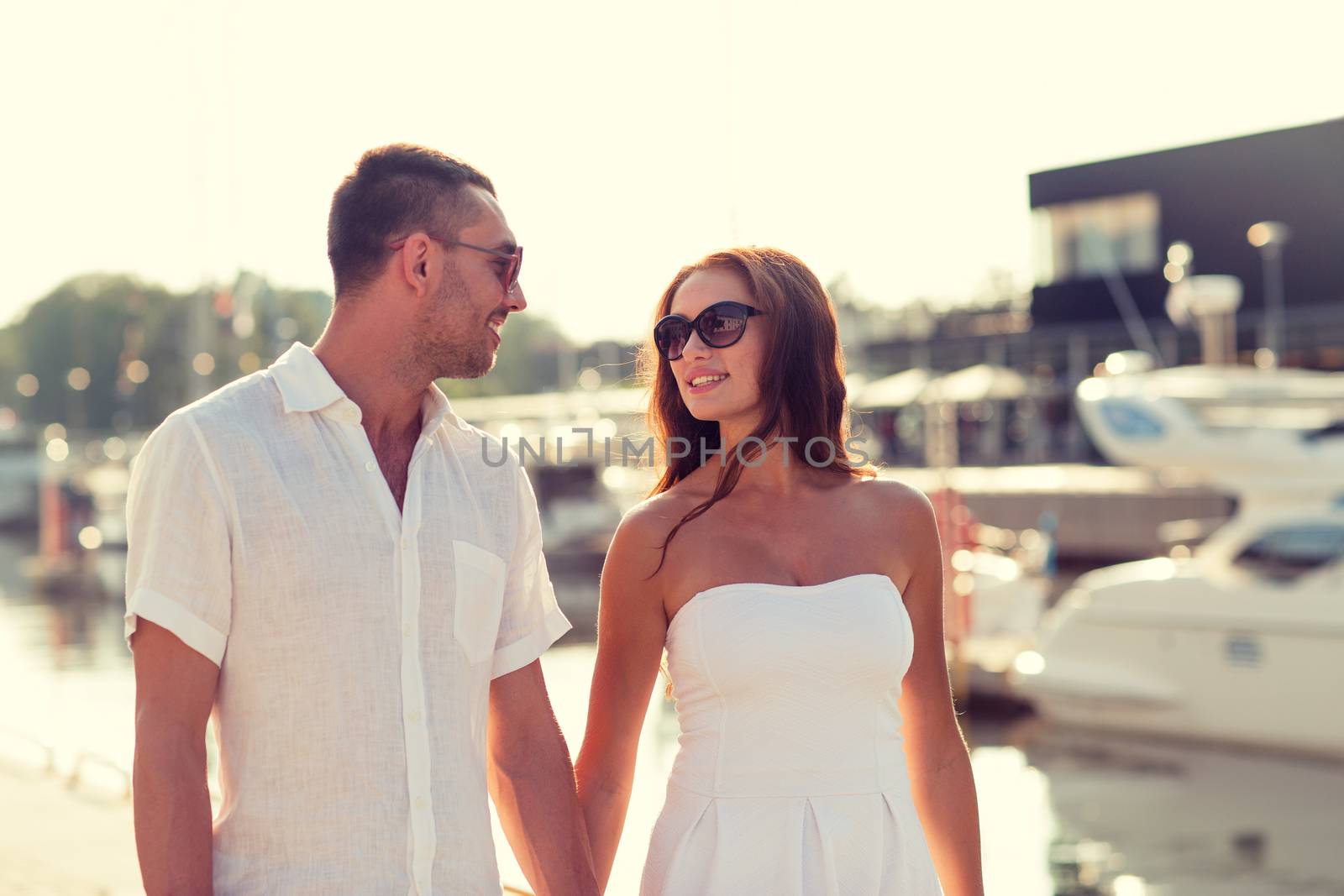 love, travel, tourism and people concept - smiling couple wearing sunglasses walking at harbor