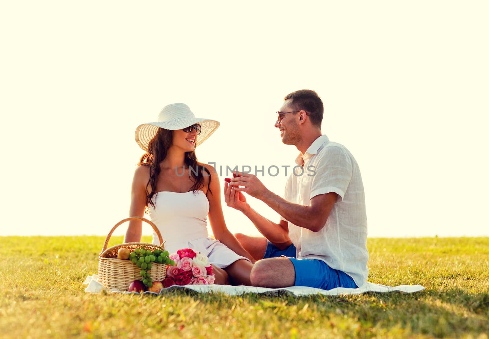 love, dating, people and holidays concept - smiling young man showing small red gift box to his girlfriend on picnic