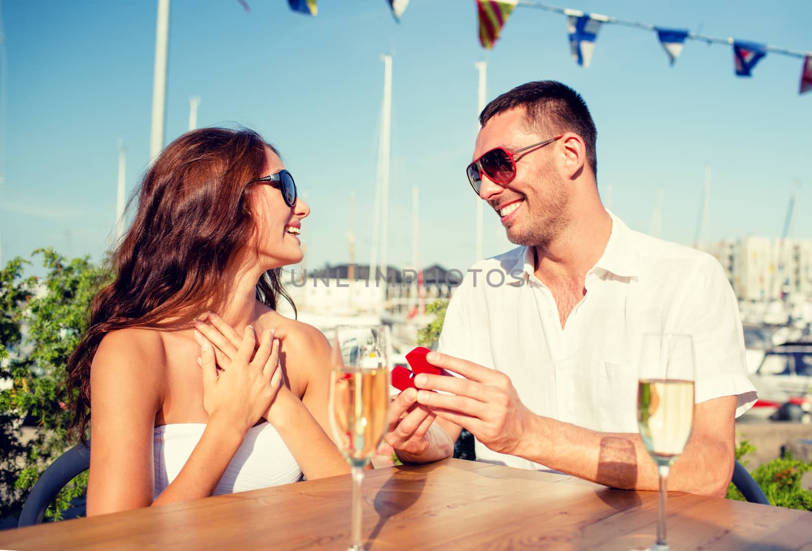 smiling couple with champagne and gift at cafe by dolgachov