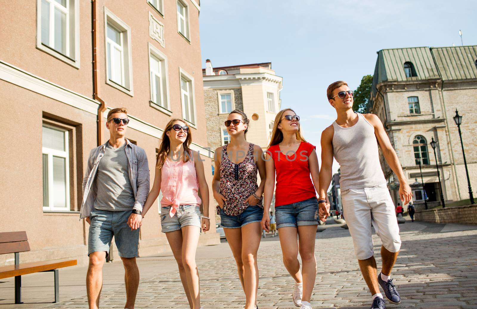 group of smiling friends walking in city by dolgachov