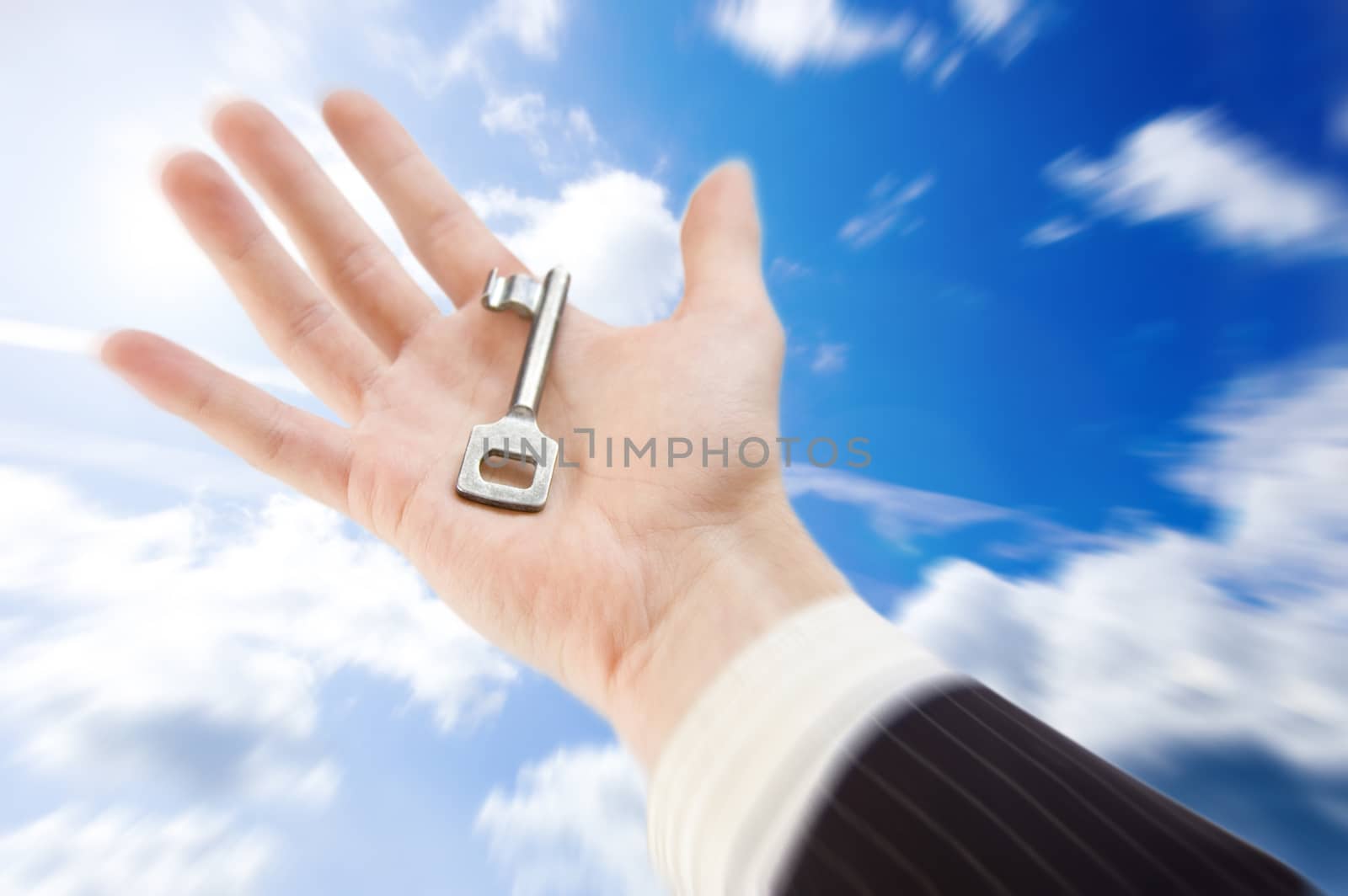 Key to success conceptual image. The businessman holds the key againts the blue sky.