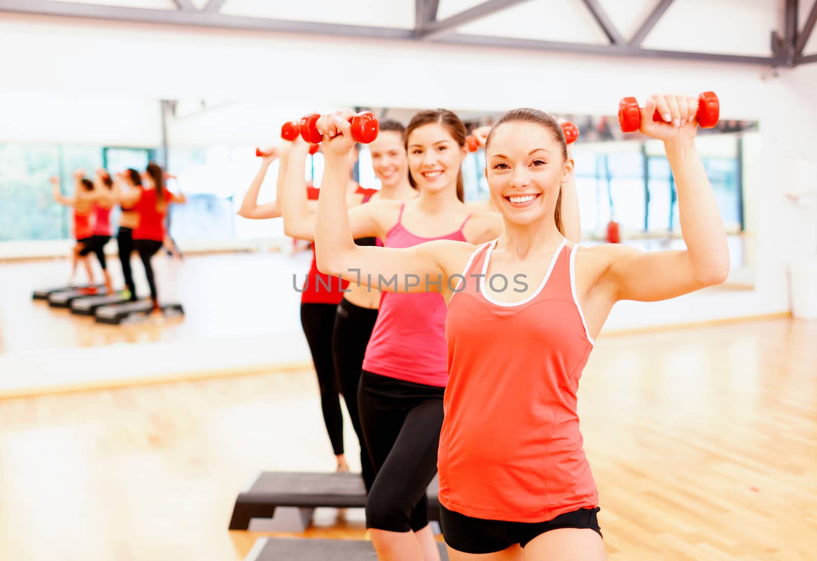 fitness, sport, training, gym and lifestyle concept - group of smiling female with dumbbells and aerobic step