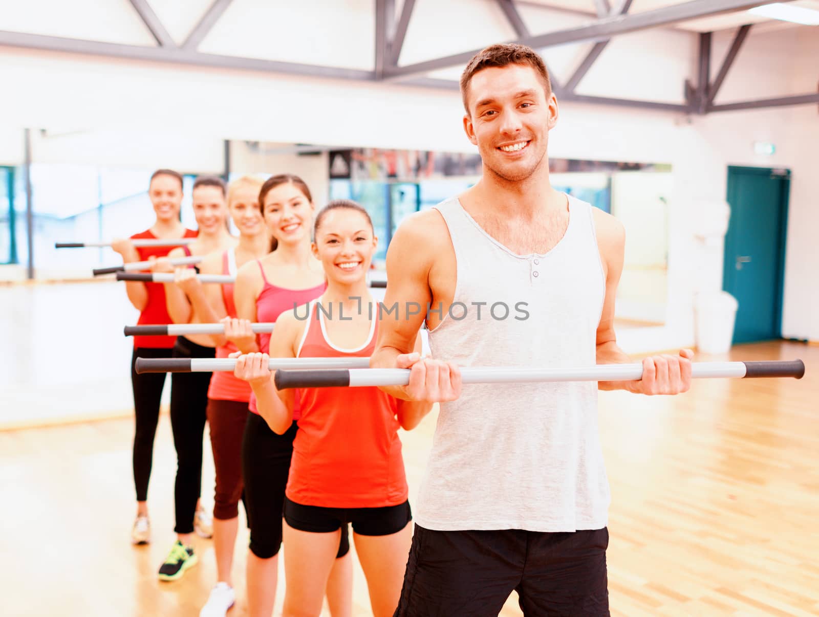 fitness, sport, training, gym and lifestyle concept - group of smiling people working out with barbells in the gym