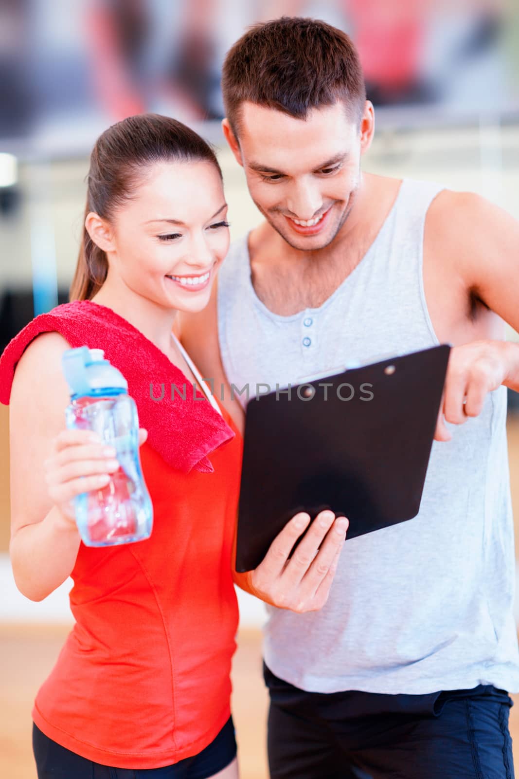 smiling male trainer with woman in the gym by dolgachov