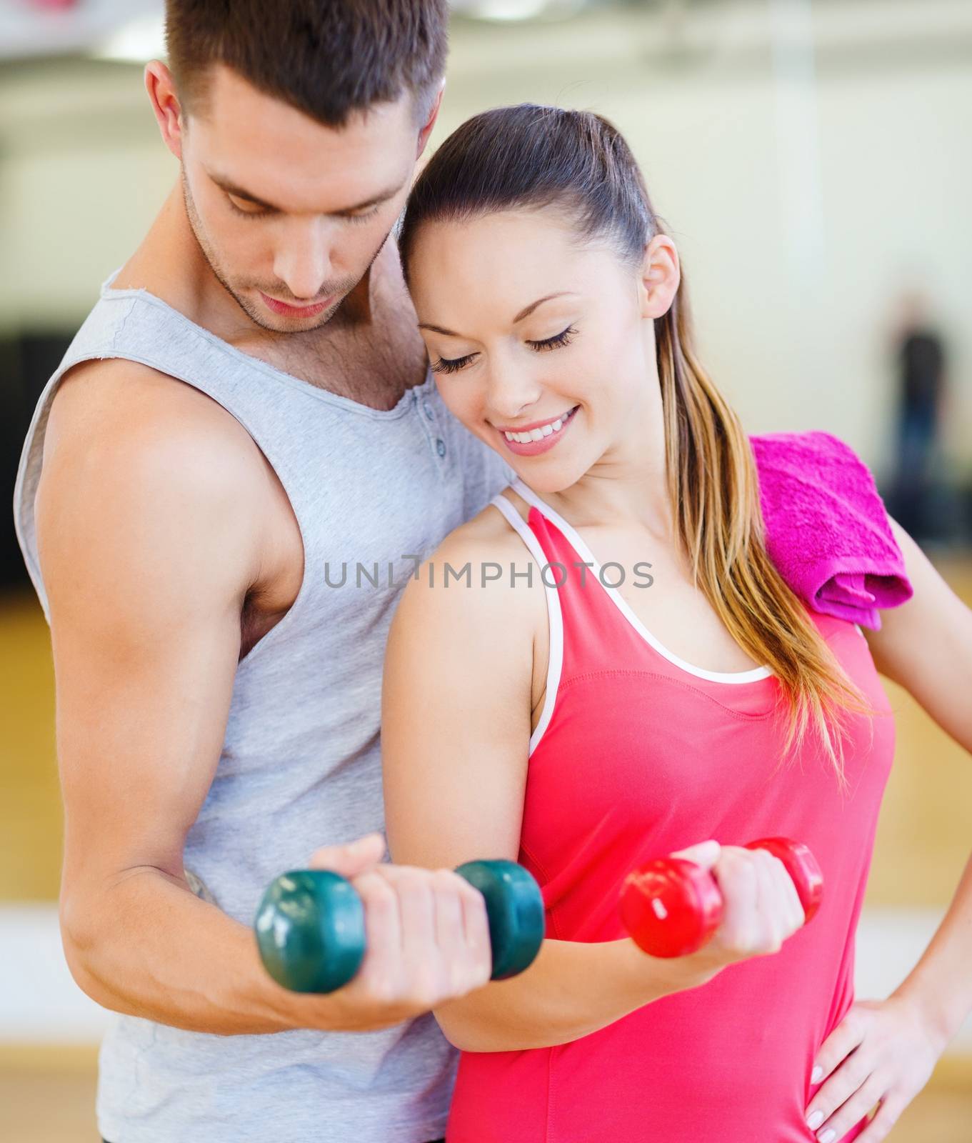 two smiling people working out with dumbbells by dolgachov