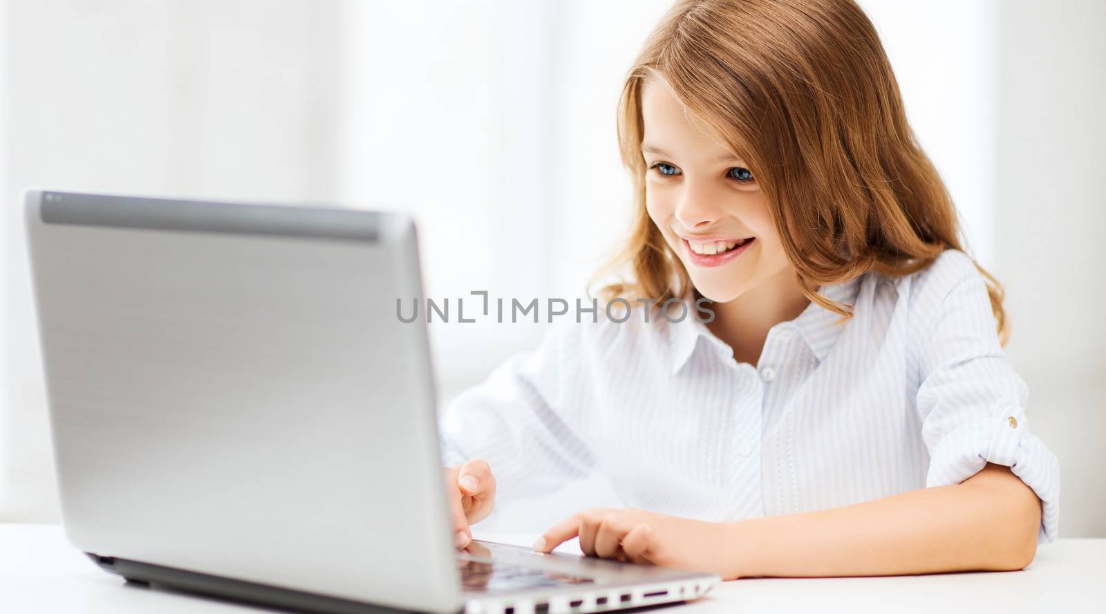 education, school, technology and internet concept - little student girl with laptop pc at school