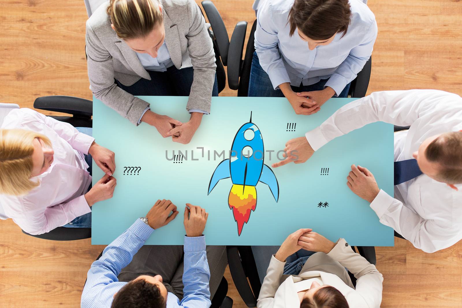 business, people, startup, development and team work concept - close up of creative team sitting at table and pointing finger to rocket icon in office