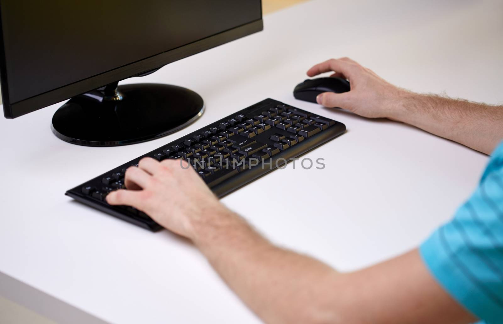 business, education, technology and internet concept - close up of male hands with computer, mouse and keyboard sitting at table