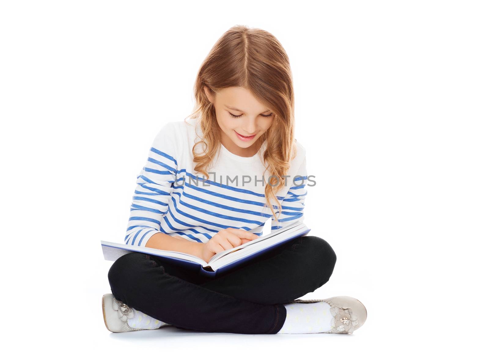 education and school concept - little student girl sitting on floor and reading book