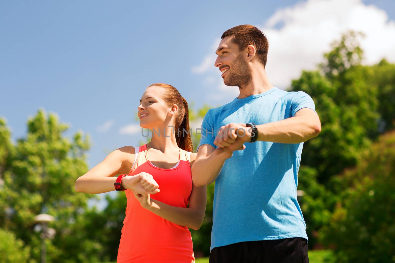 smiling people with heart rate watches outdoors by dolgachov