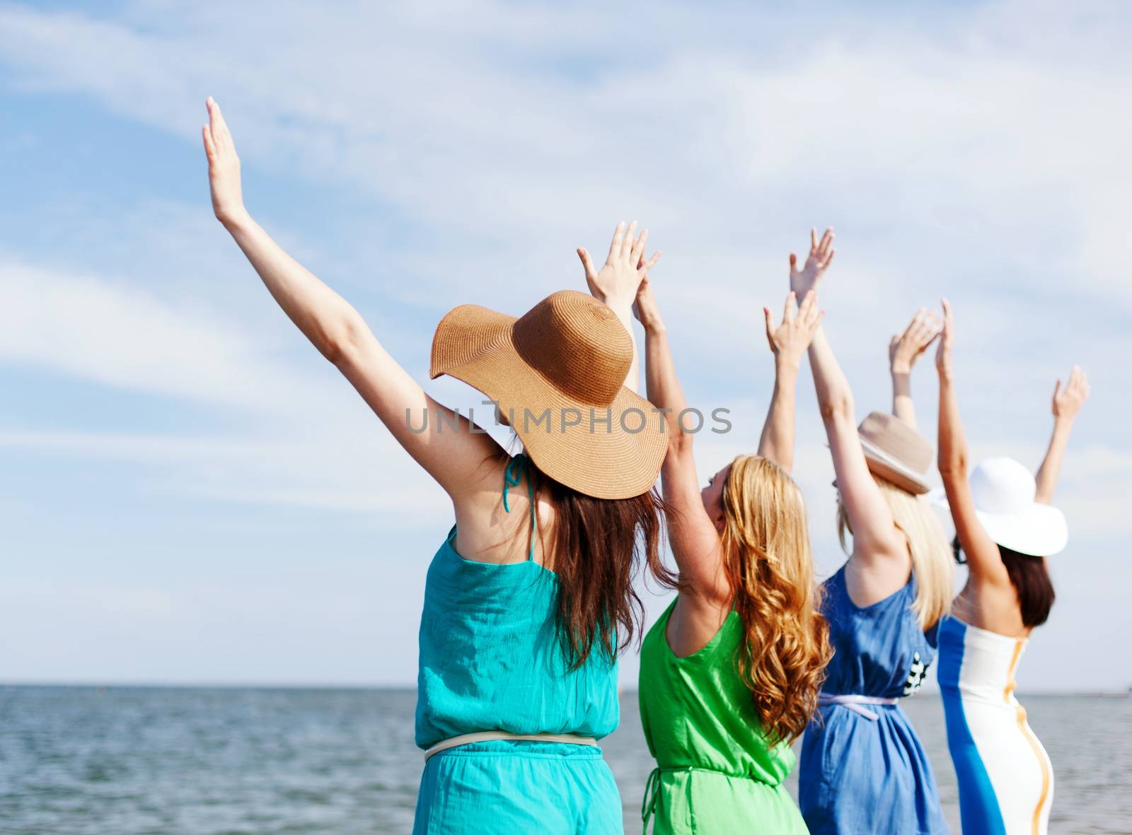 girls looking at the sea with hands up by dolgachov