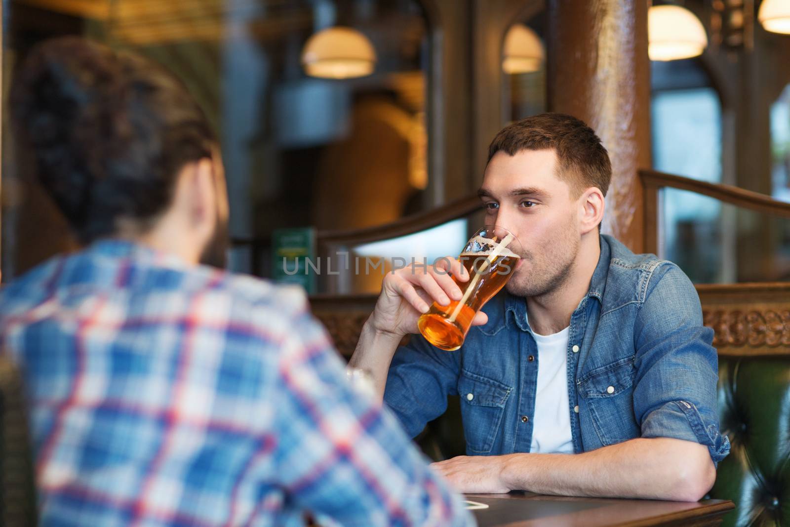 happy male friends drinking beer at bar or pub by dolgachov