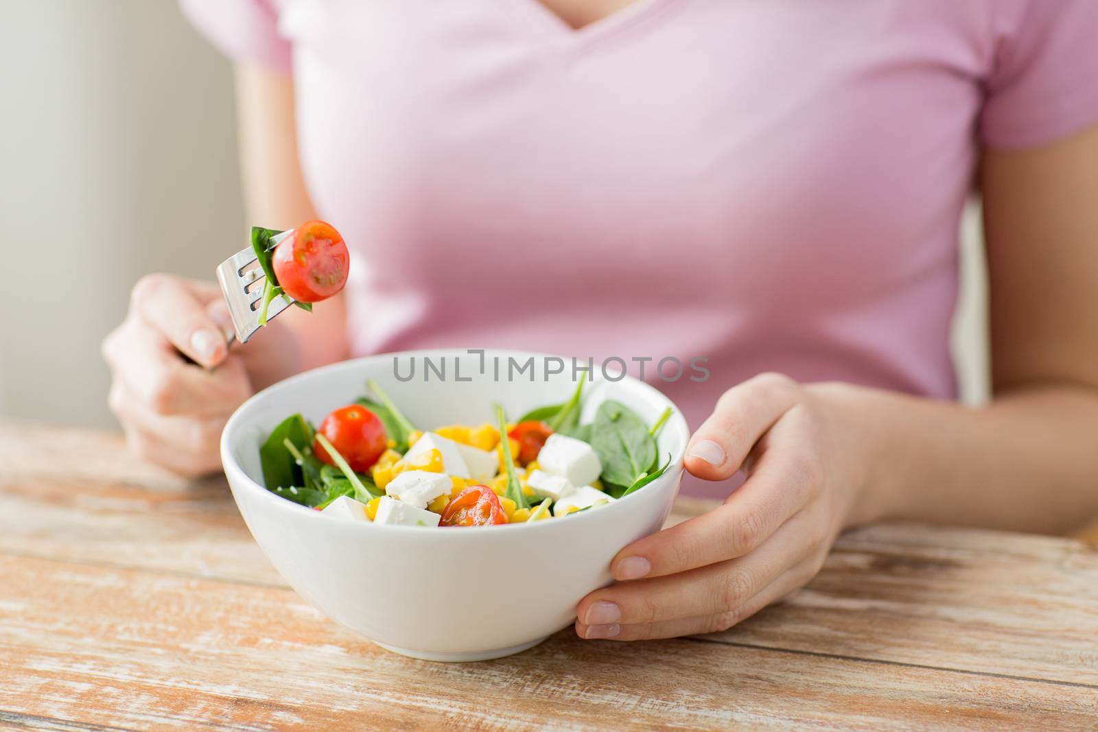 close up of young woman eating salad at home by dolgachov