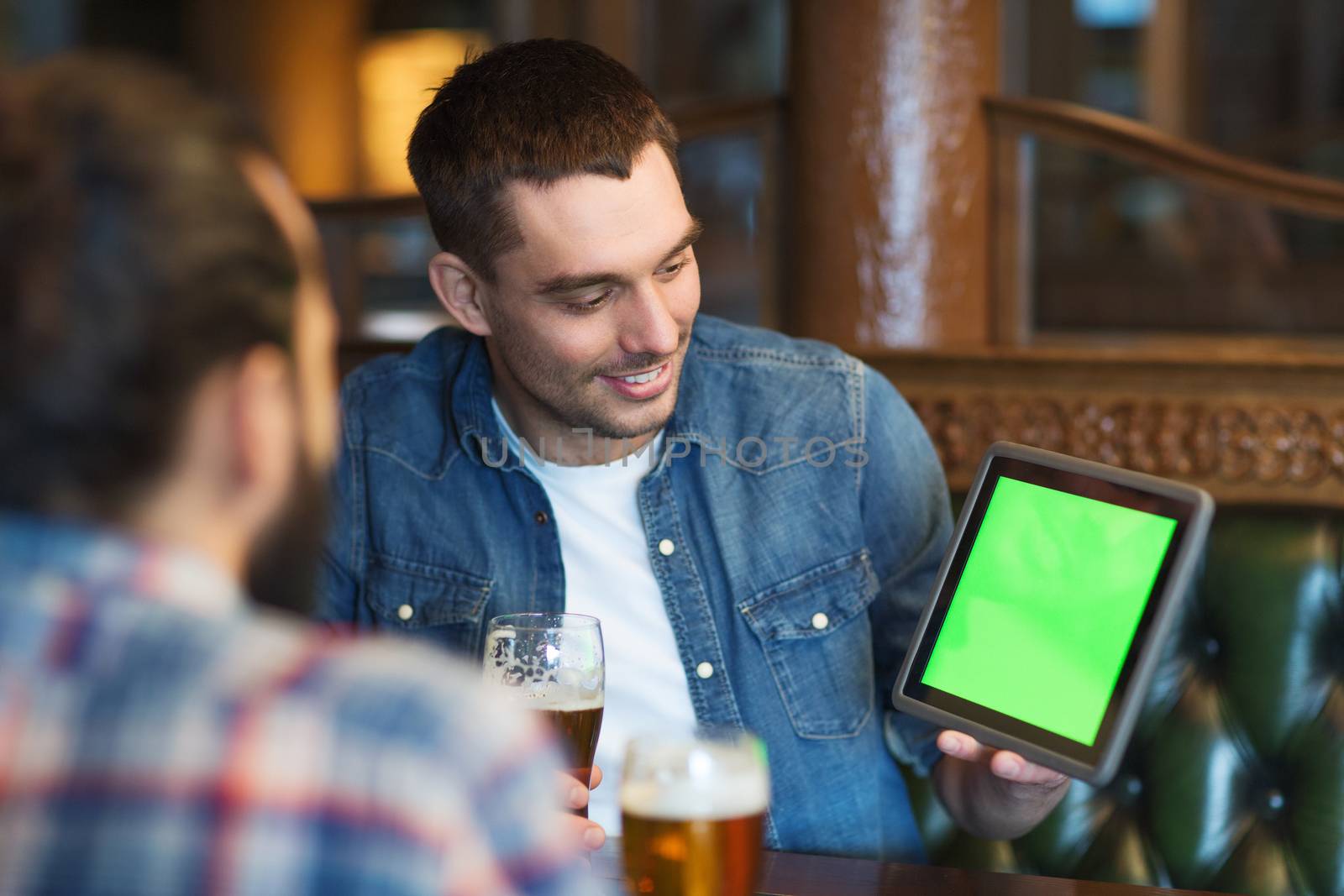 male friends with tablet pc drinking beer at bar by dolgachov