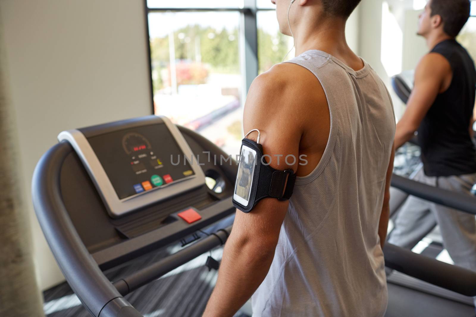 sport, fitness, lifestyle, technology and people concept - smiling men exercising on treadmill in gym