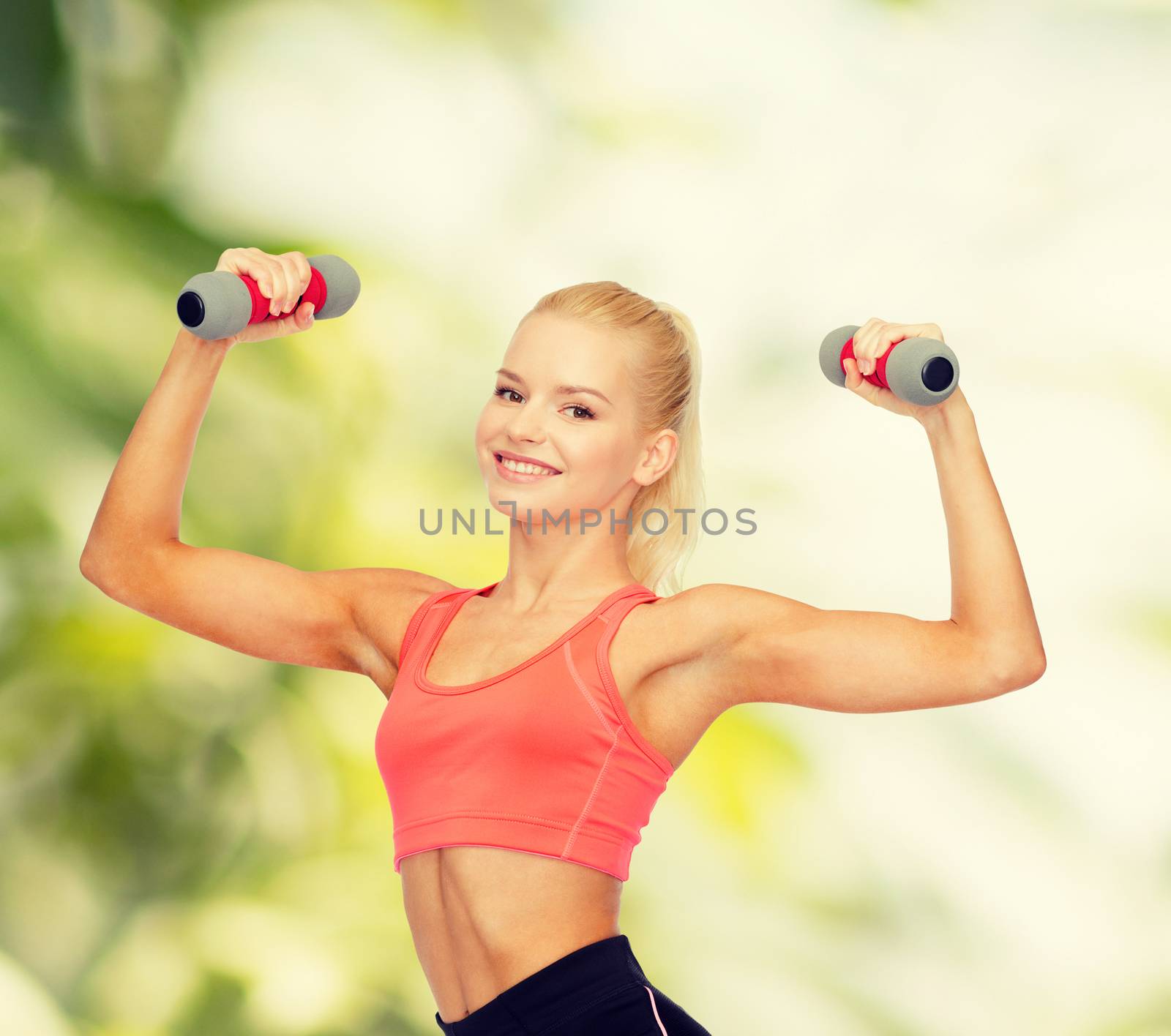 smiling beautiful sporty woman with dumbbells by dolgachov