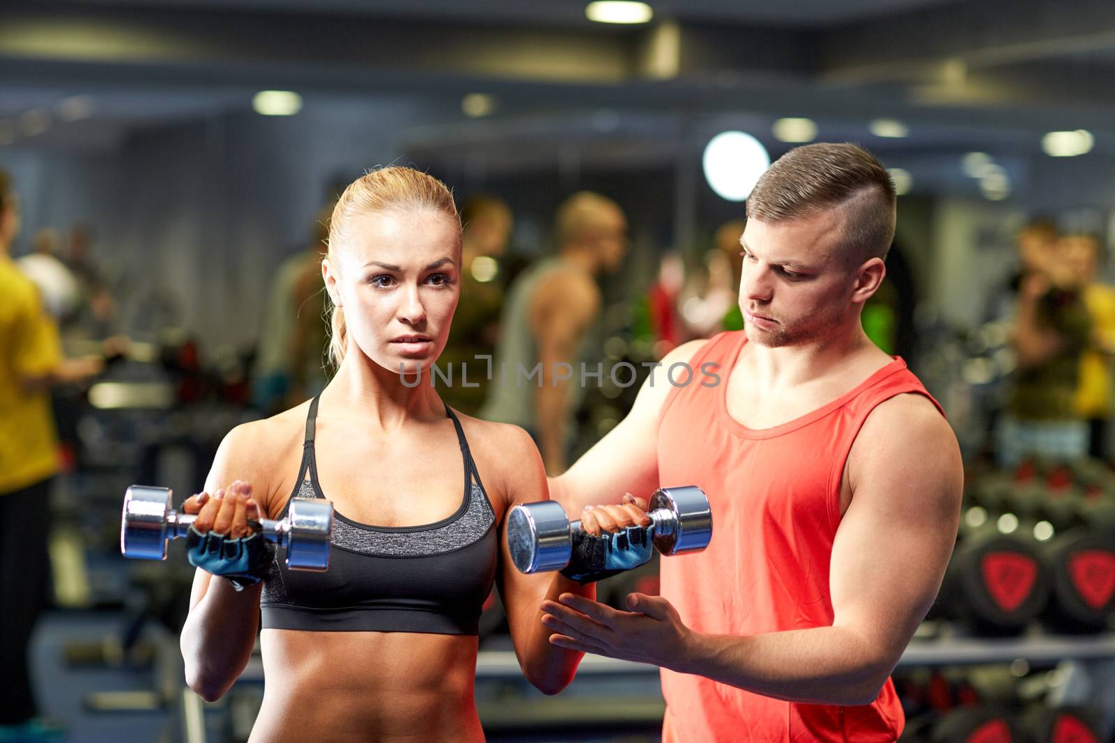 young couple with dumbbells flexing muscles in gym by dolgachov