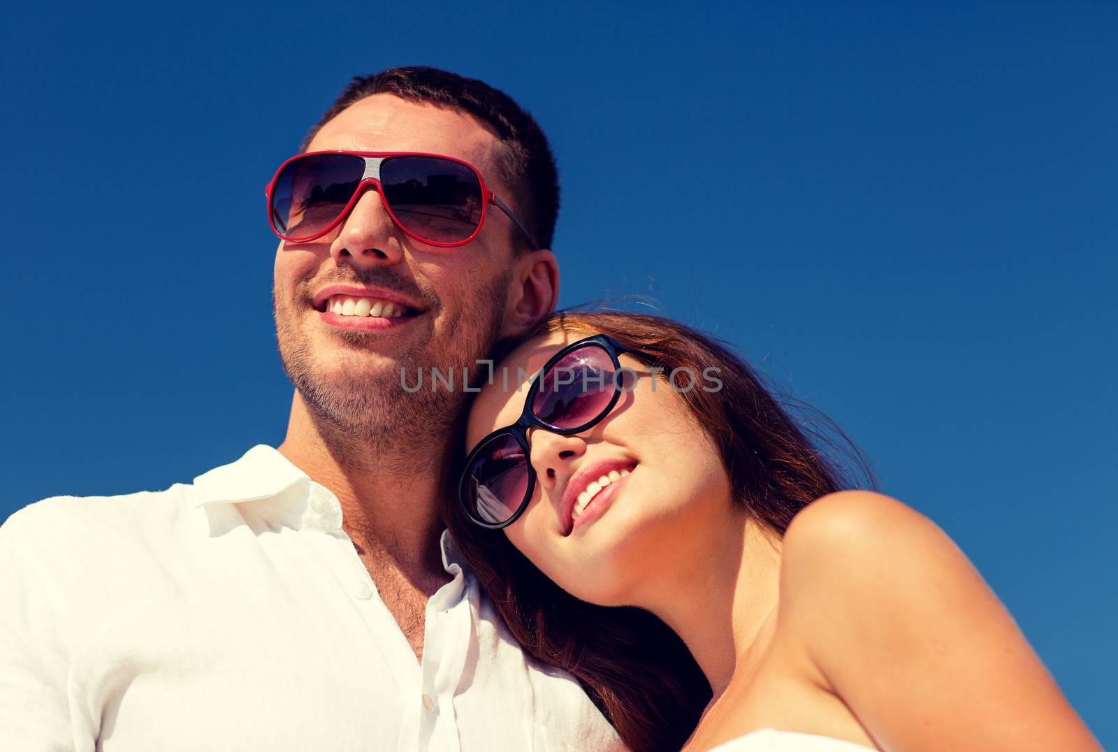 smiling couple over blue sky background by dolgachov