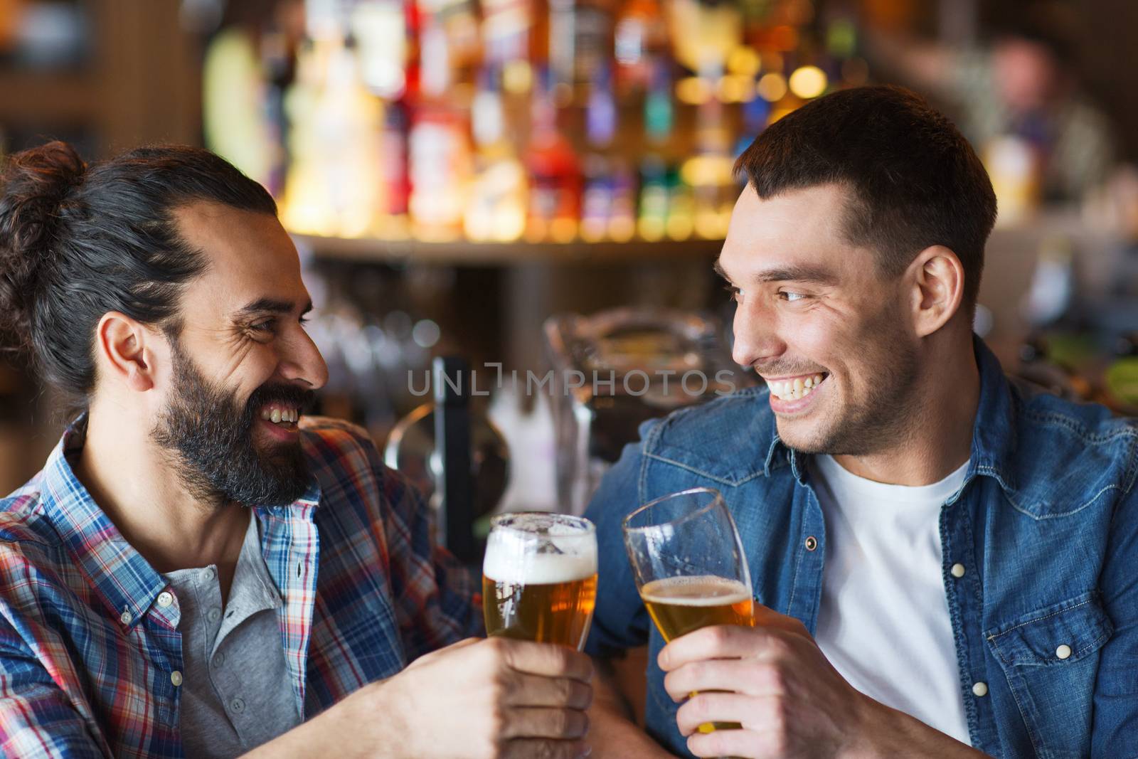 people, men, leisure, friendship and celebration concept - happy male friends drinking beer and clinking glasses at bar or pub