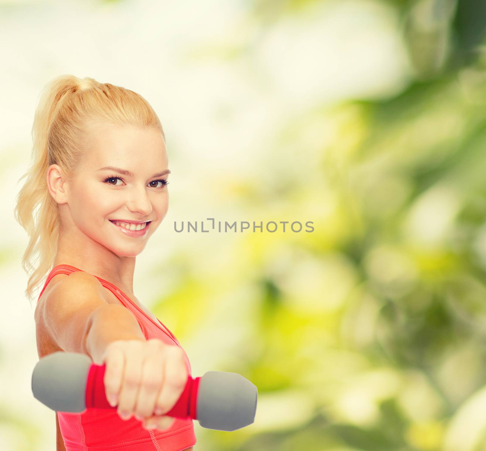 smiling beautiful sporty woman with dumbbell by dolgachov