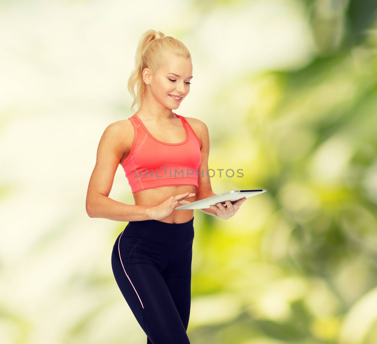 smiling sporty woman with tablet pc computer by dolgachov