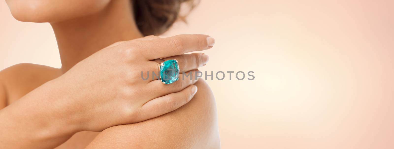 beauty, jewelry, people and accessories concept - close up of woman with cocktail ring on hand over beige background