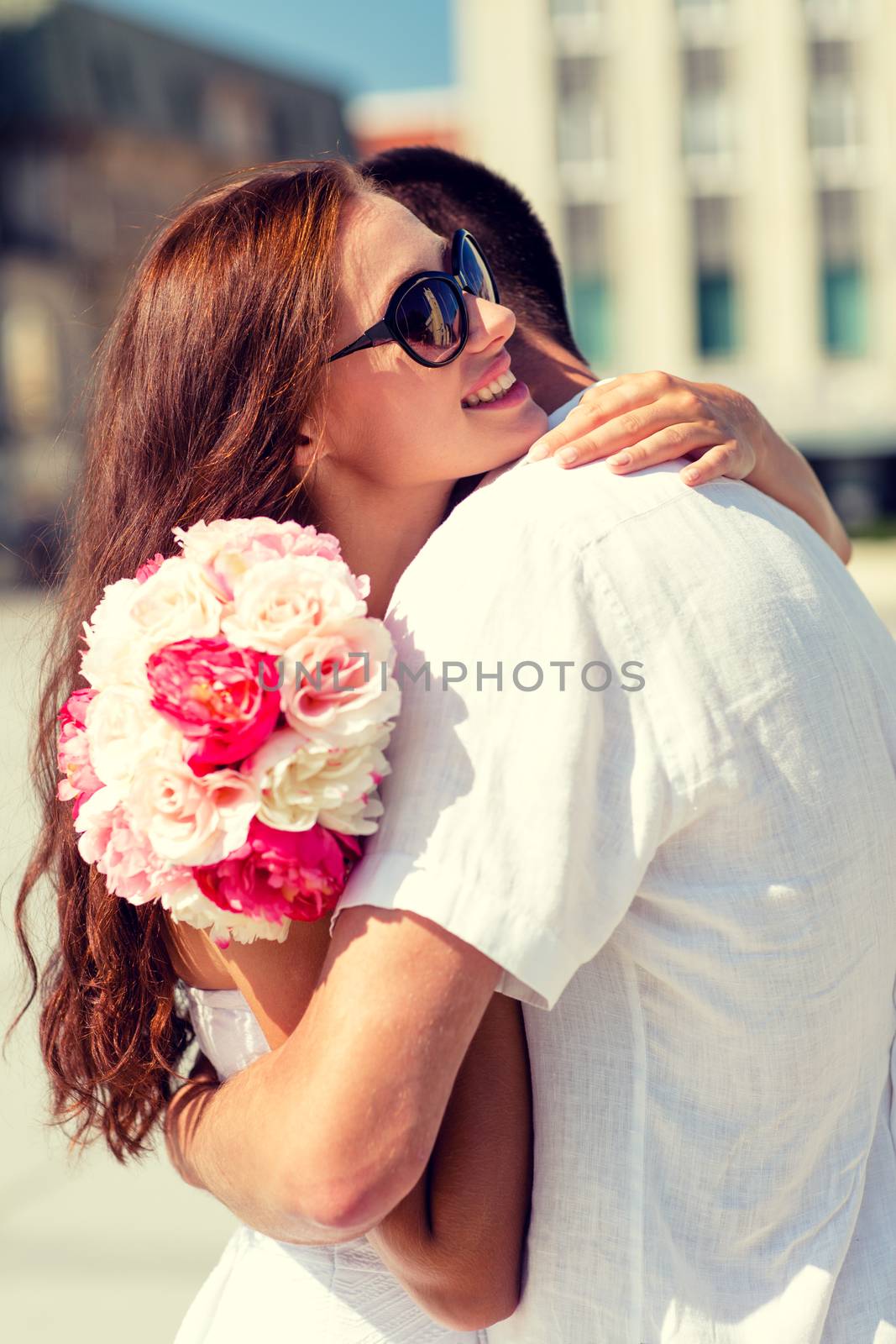 love, wedding, summer, dating and people concept - smiling couple wearing sunglasses with bunch of flowers hugging in city