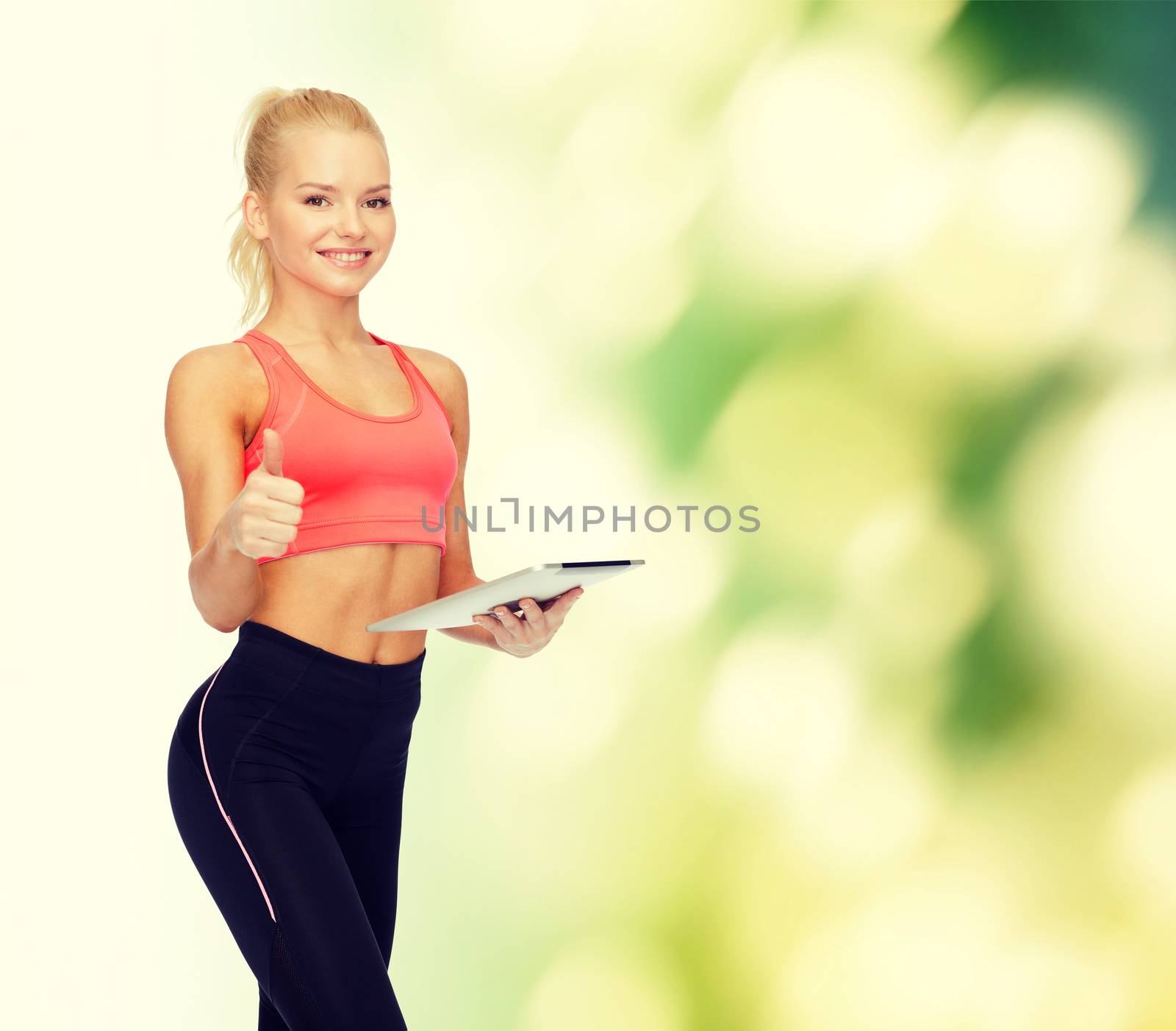 smiling sporty woman with tablet pc computer by dolgachov
