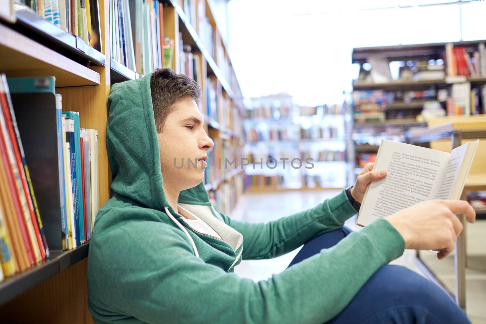 student boy or young man reading book in library by dolgachov