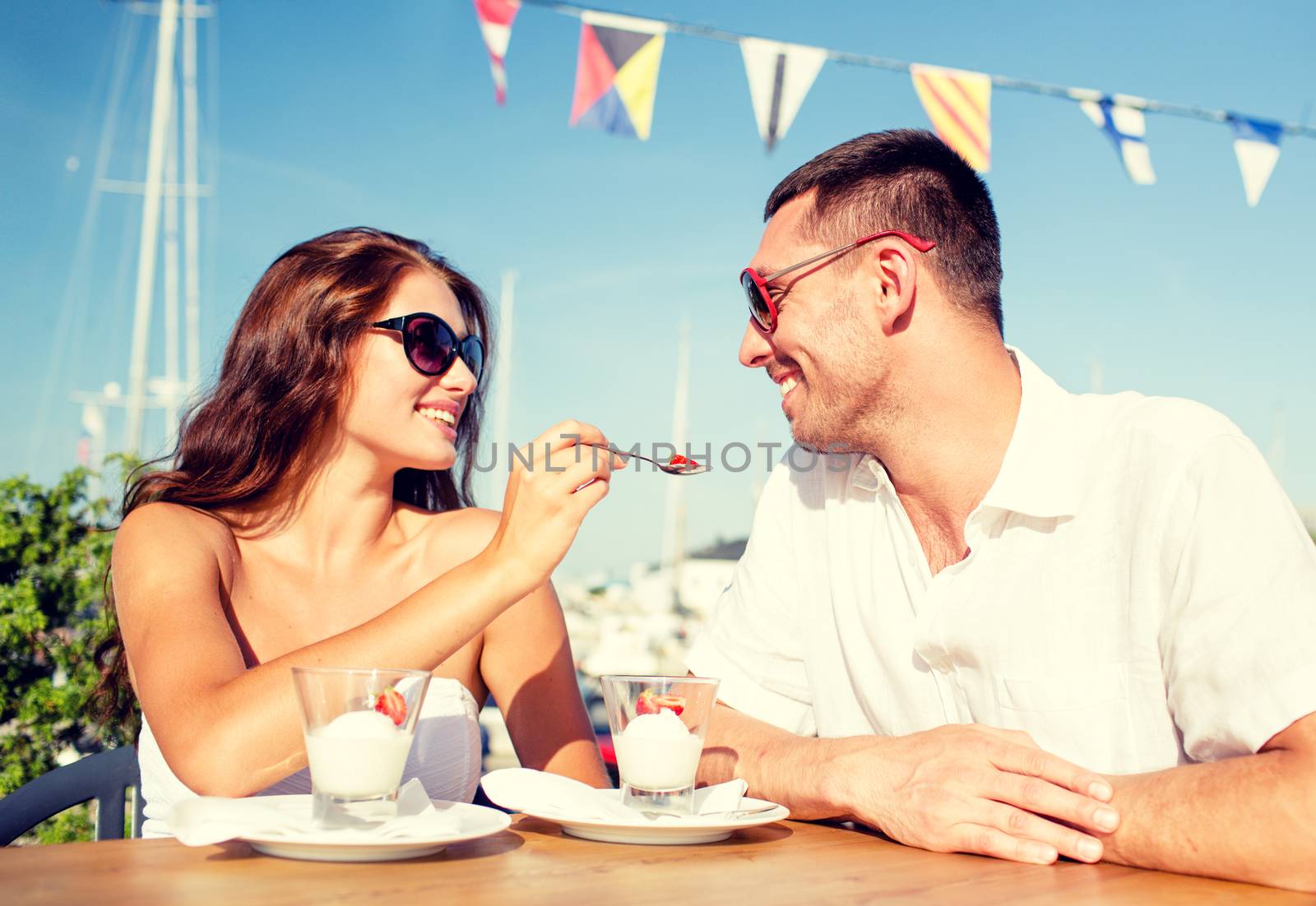 smiling couple eating dessert at cafe by dolgachov