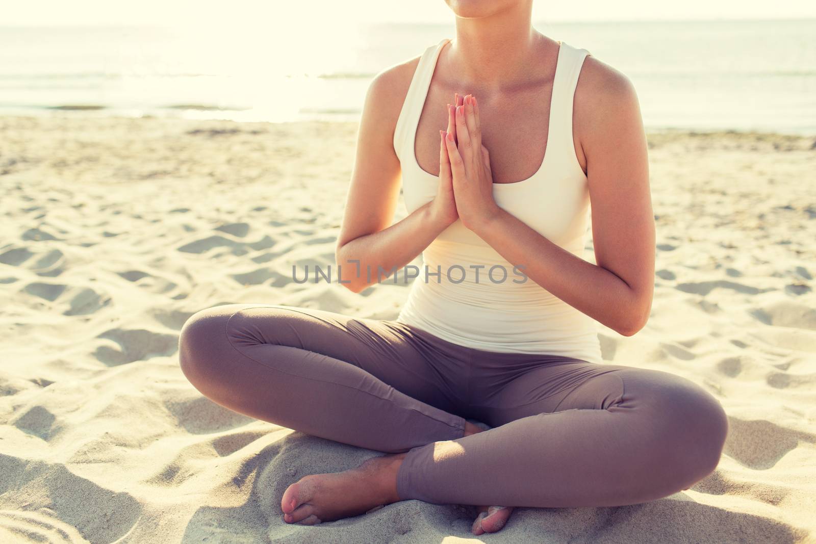 fitness, sport, people and lifestyle concept - close up of woman making yoga exercises on pier outdoors